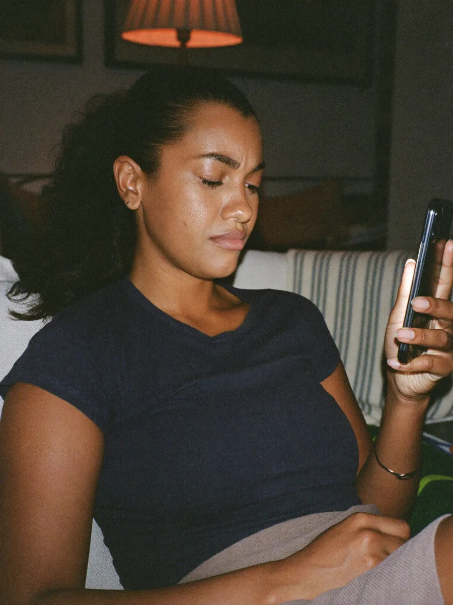 Mulher no sofá à noite procurando uma clínica pelo celular